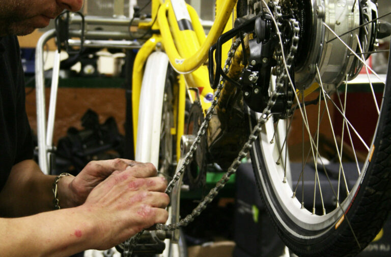 Prestation AAPH: Entretien et réparation de vélo, un homme aux mains assez abimées par le travail s'occupe de la réparation d'un vélo